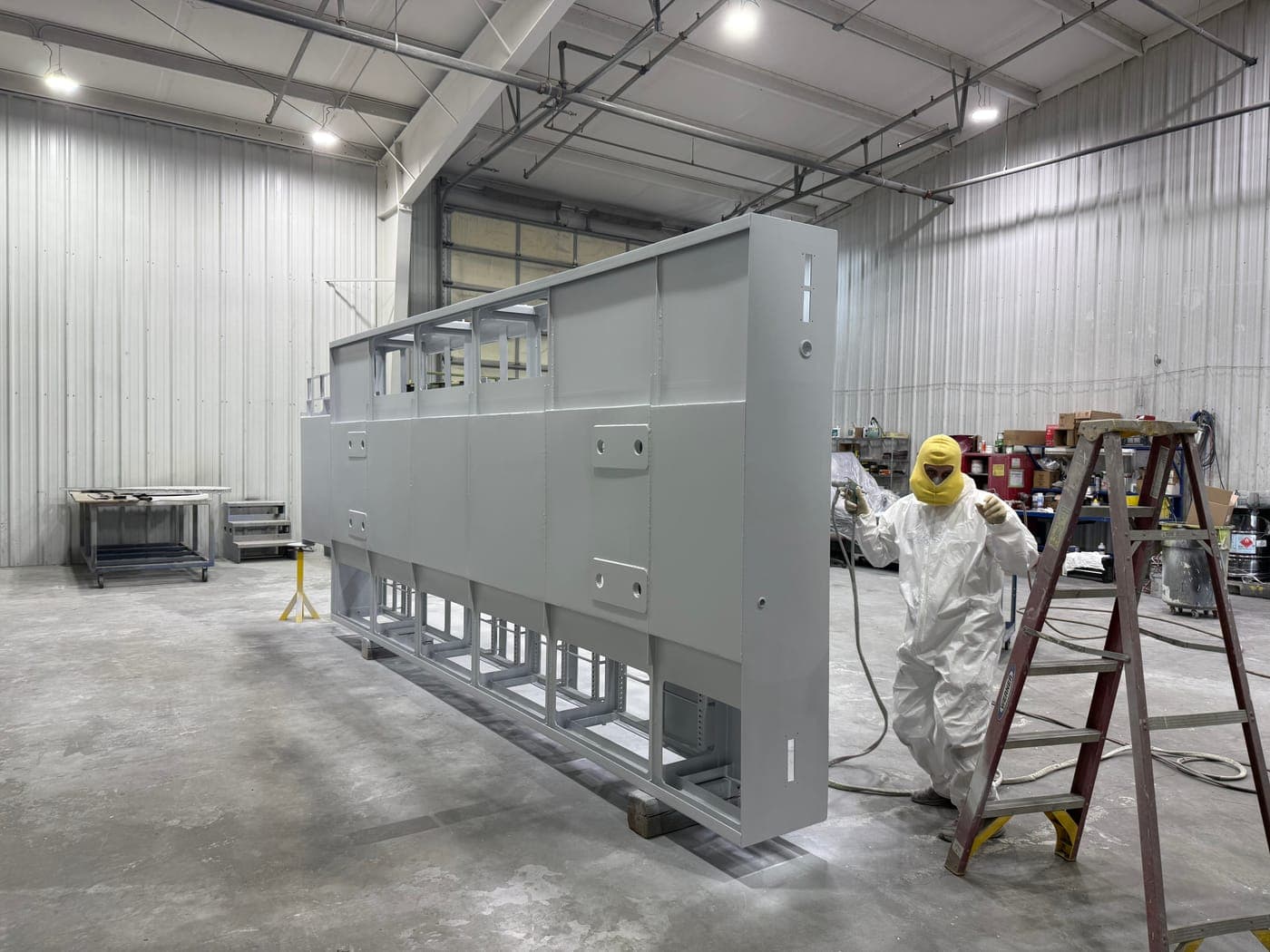 Worker coating a large industrial enclosure in the Werco paint booth