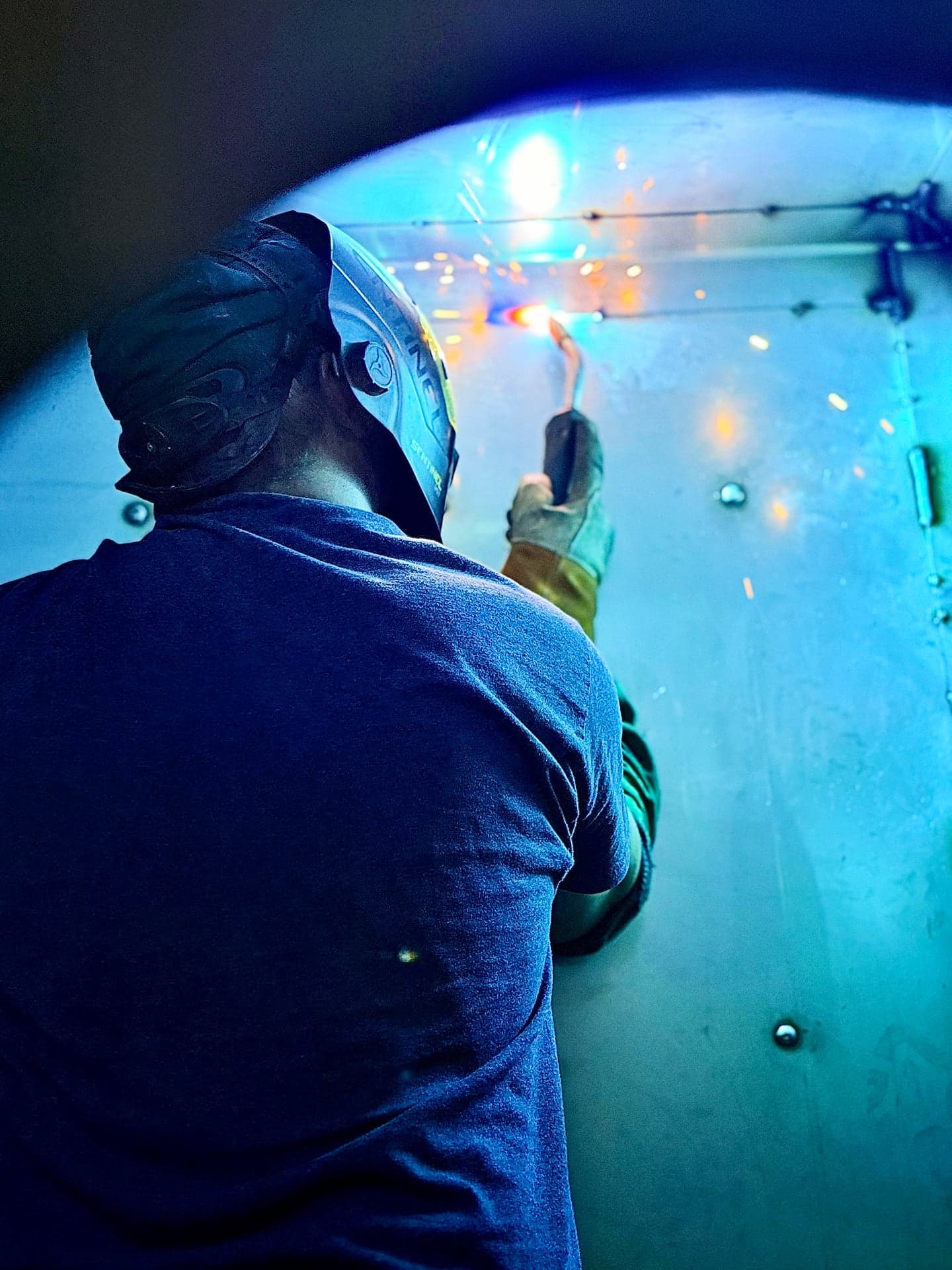 Welder working on a metal assembly with a bright welding arc and sparks